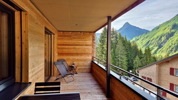 Ein Holzbalkon mit Blick auf einen Berg und einen Wald.