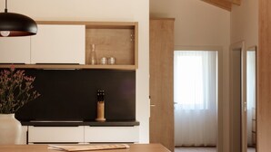 Una cocina moderna con vigas de madera, encimera negra y una lámpara colgante.