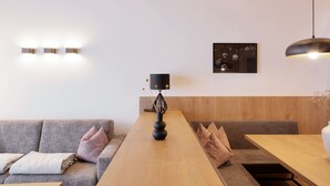 Un interior moderno con una mesa de comedor de madera, un sofá gris y una lámpara negra.