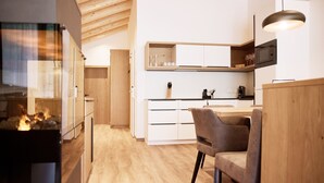 Uma cozinha moderna com armários brancos, teto de madeira e área de jantar com mesa e cadeiras.