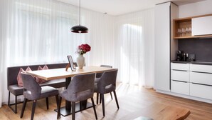 Un espace de salle à manger moderne, avec une table en bois, des chaises à revêtement gris et un vase rempli de fleurs rouges.