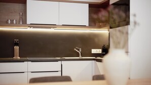 Una cocina moderna con una encimera elegante, un grifo de acero inoxidable y un jarrón en la mesa.