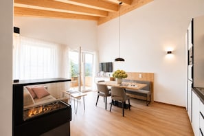 A modern living room with a fireplace, a dining area, and a kitchen with a TV.