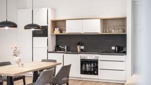 A modern kitchen with white cabinets, a black countertop, and a built-in oven.