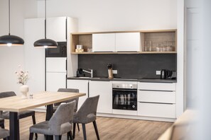 A modern kitchen with white cabinets, a black countertop, and a built-in oven. - Alpenstolz #4.01 Comfort (Damüls)