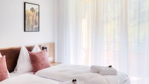 A modern hotel room with a large bed, white linens, and a headboard with pink pillows.