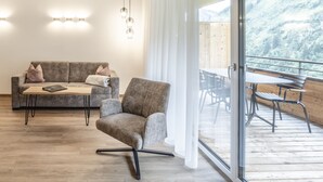 A modern living room with a sofa, armchair, and a dining table with chairs. - Alpenstolz #4.03 Comfort (Damüls)