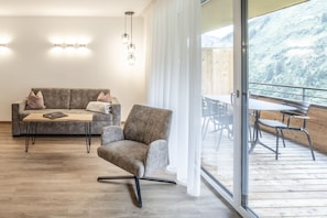 A modern living room with a sofa, armchair, and a dining table with chairs. - Alpenstolz #4.03 Comfort (Damüls)