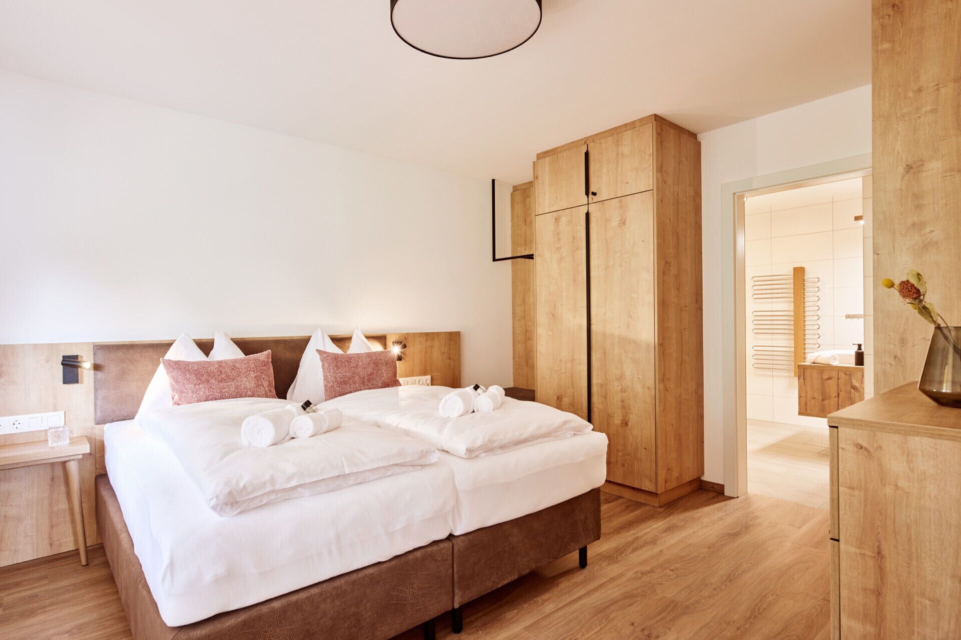 A modern bedroom with a large bed, wooden headboard, and built-in wardrobe.