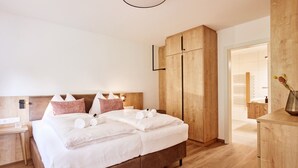 Quarto moderno com cama grande, cabeceira de madeira e armário embutido.