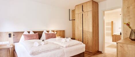 A modern bedroom with a large bed, wooden headboard, and built-in wardrobe.