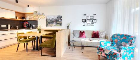A modern kitchen with a dining area, a sofa, and a floral armchair.