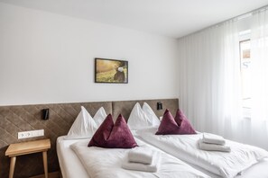 A hotel room with a bed, pillows, a bedside table, a power outlet, and a painting on the wall. - Alpenstolz #4.09 Exklusive with coolfire (Damüls)