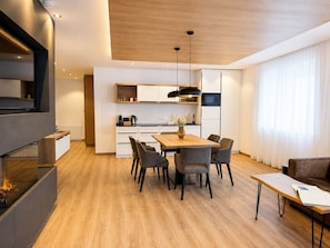 A modern kitchen with white cabinets, a wooden dining table, and a built-in oven.