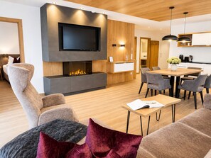 A modern living room with a flat-screen TV, a fireplace, and a dining area with a table and chairs.