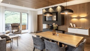 A modern dining area with a wooden table, grey upholstered chairs, and pendant lighting. - Alpenstolz #4.09 Exklusive with coolfire (Damüls)