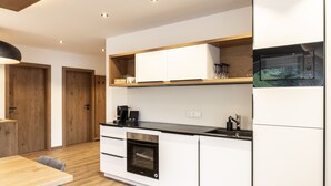 Une cuisine moderne avec des meubles blancs, un four encastré et un micro-ondes.