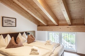 A bedroom with a wooden ceiling, a bed with white linens, and a framed feather artwork on the wall. - Alpenstolz #4.10 Comfort (Damüls)