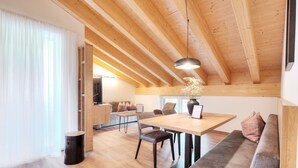 A modern interior with a wooden ceiling, a dining area with a table and chairs, a sofa, and a small side table. - Alpenstolz #4.13 Comfort (Damüls)