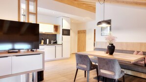 A modern kitchen with white cabinets, a built-in microwave, and a large flat-screen TV. - Alpenstolz #4.13 Comfort (Damüls)
