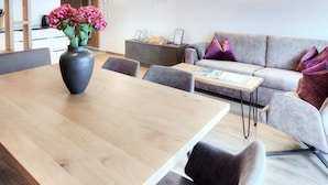 A modern living room with a wooden dining table, grey sofa, and a vase of flowers. - Alpenstolz #4.11 Exclusive with coolfire (Damüls)