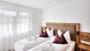 A hotel room with a bed, white linens, a wooden headboard, and a window with sheer curtains. - Alpenstolz #4.11 Exclusive with coolfire (Damüls)