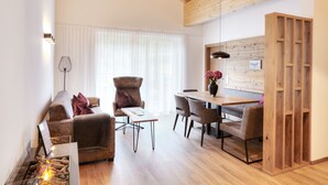 A modern living room with a sofa, armchair, dining table, and a fireplace. - Alpenstolz #4.11 Exclusive with coolfire (Damüls)