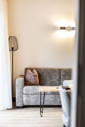 A modern living room with a grey sofa, a floor lamp, and a wall-mounted light fixture.