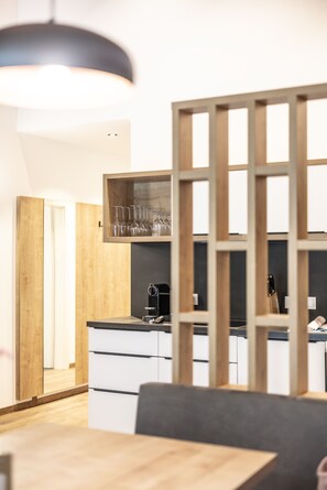 A modern kitchen with wooden cabinets, a coffee machine, and a wine rack. - Alpenstolz #4.12 Comfort (Damüls)
