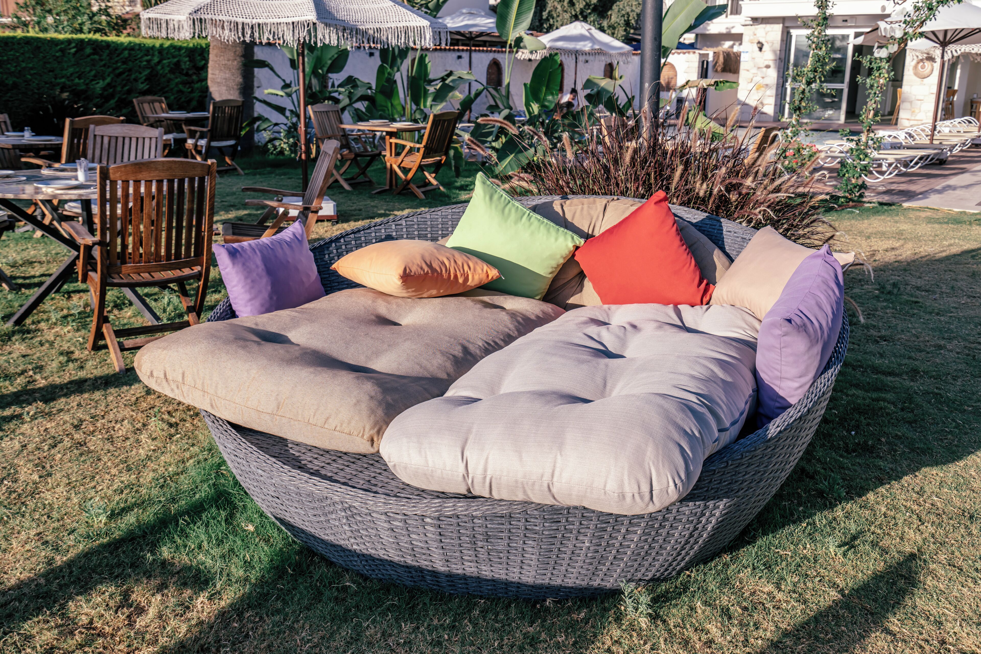Zona relax esterna con mobili in vimini, cuscini e un tavolo con sedie.