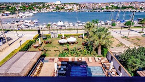 A rooftop pool area with lounge chairs, umbrellas, and a view of a marina with boats. - Sirius Mi Sun Paradise (Cesme)