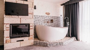 A modern bathroom with a freestanding bathtub, a built-in fireplace, and patterned tiles. - Sirius Mi Sun Paradise (Cesme)