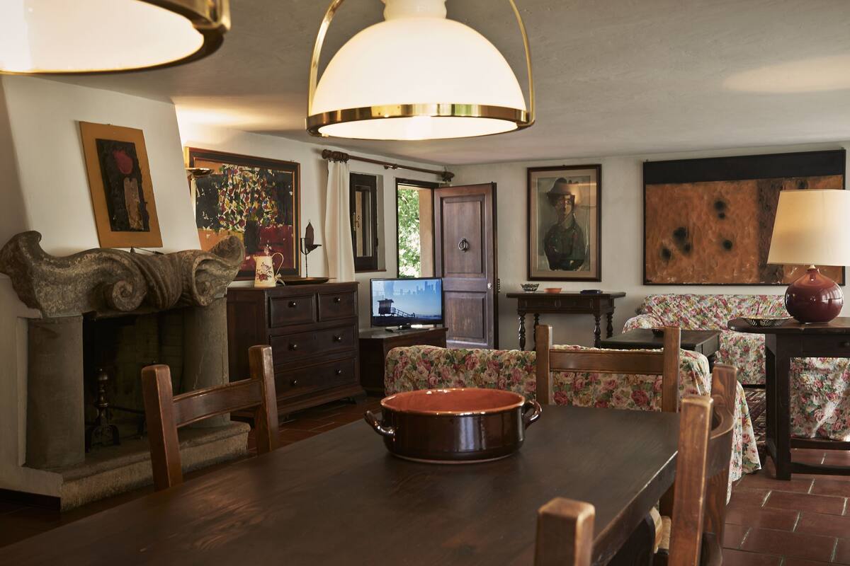 Ein Essbereich mit einem Holztisch, Stühlen, einem großen Topf und einem Fernseher.