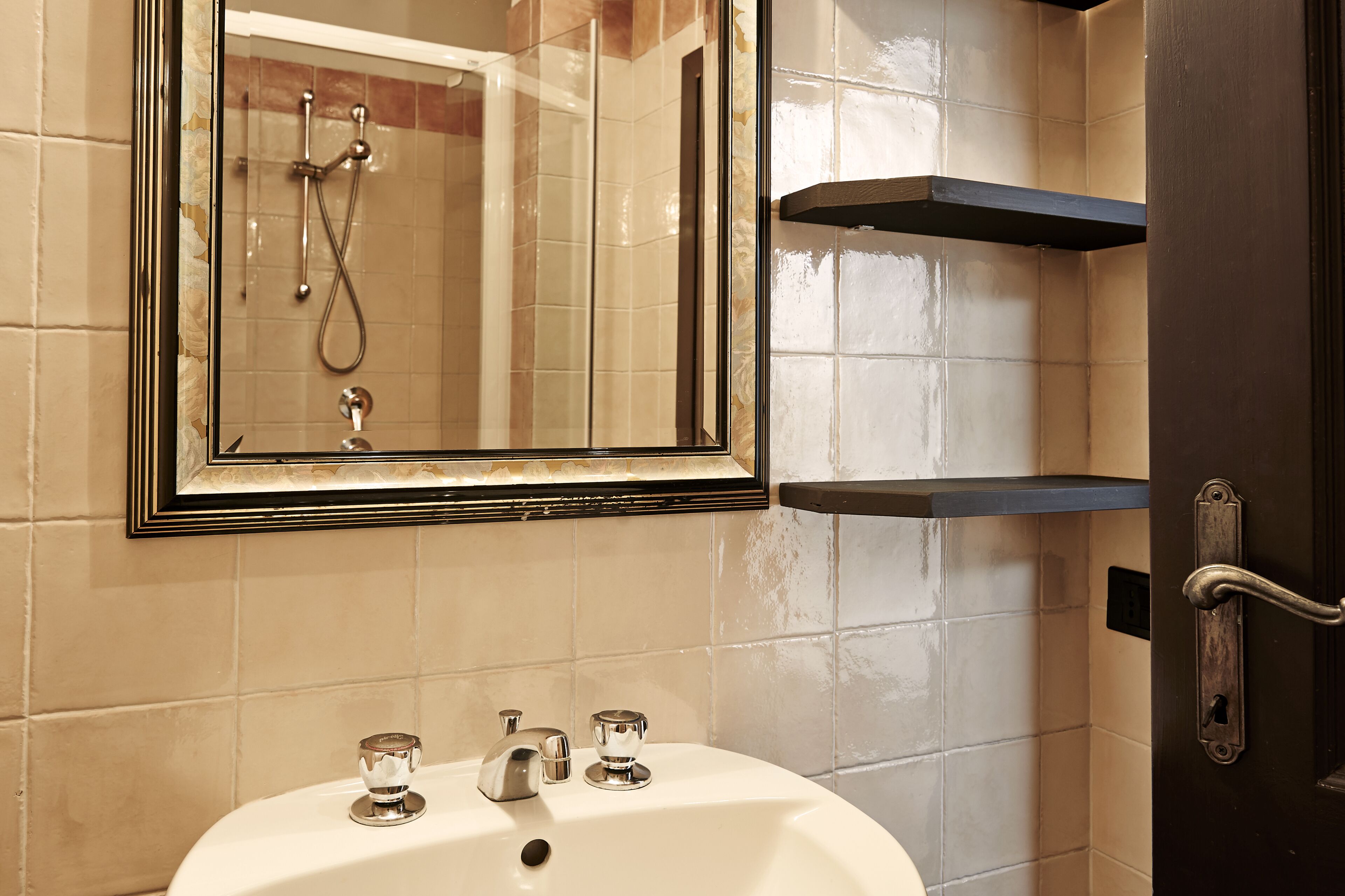 Un baño con un lavabo blanco, un espejo y una ducha.