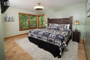A bedroom with a large bed, two windows with blinds, a ceiling fan, a bedside table with a lamp, and a rug on the floor. - 3br, sleeps 10, Gatlinburg, all the amenities! (Gatlinburg)