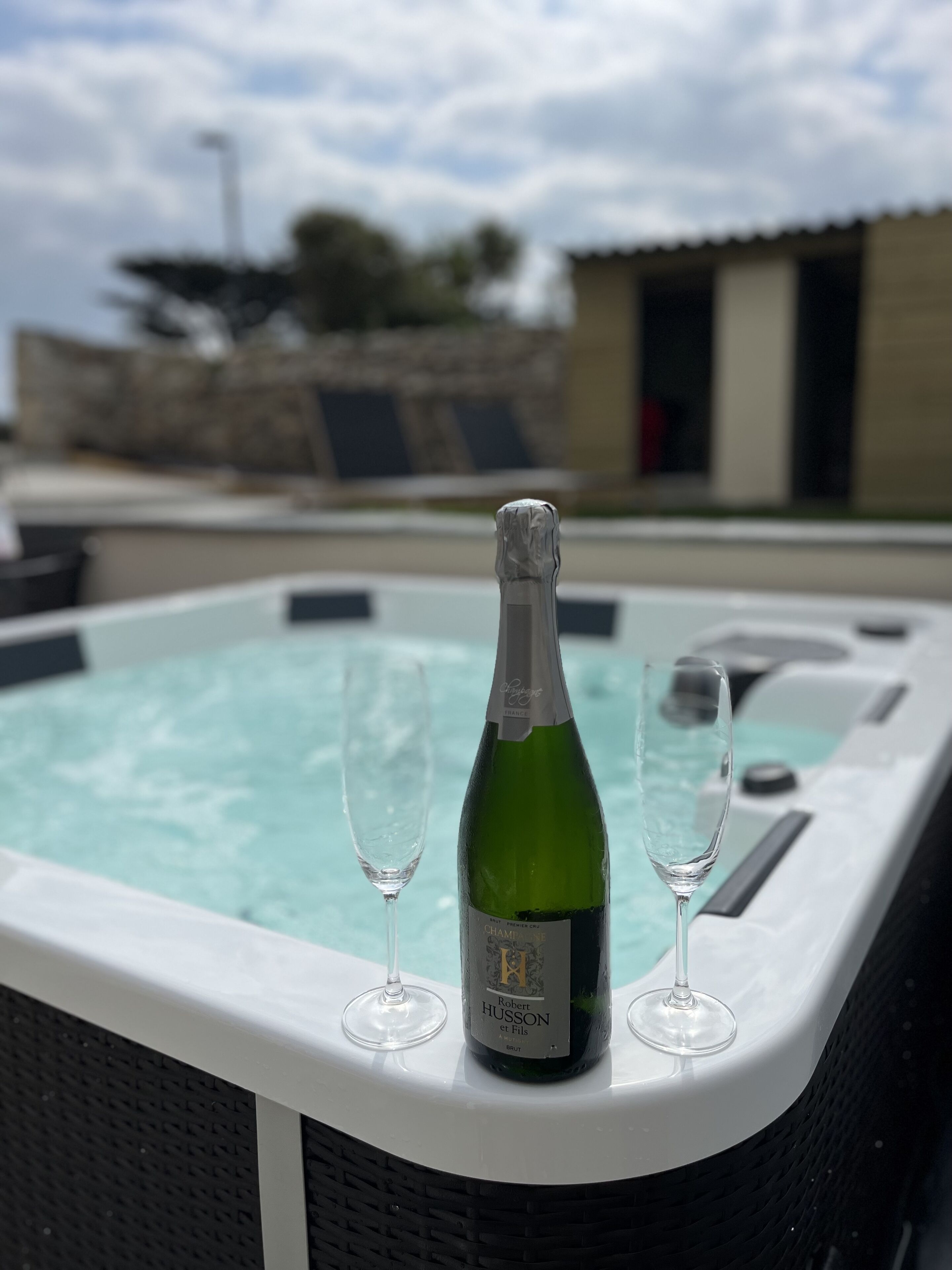 Eine Champagnerflasche und zwei Gläser in einer weißen Whirlpool-Badewanne.
