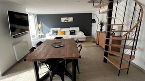 Una sala de estar moderna con una mesa de comedor, sofá y una escalera en espiral.