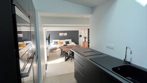 Una cocina moderna con tragaluces, una zona de comedor con mesa de madera y vista al salón.