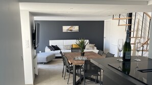 Una cocina moderna con comedor, una escalera y una sala de estar con sofá y un cuadro.