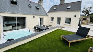 Una casa moderna con piscina, un patio con mesa y sillas, y un jardín.