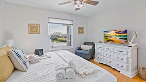 A bedroom with a large bed, a view of a river, a desk with a laptop, and a white dresser. - Private heated Pool/Gym/Games/Sauna/Massage Chair (Hernando Beach)