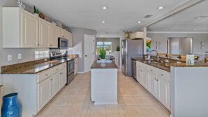 A modern kitchen with white cabinetry, granite countertops, and stainless steel appliances. - Private heated Pool/Gym/Games/Sauna/Massage Chair (Hernando Beach)