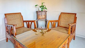 Una mesa de comedor con cuatro sillas de madera, una mesita auxiliar con una planta y un tablero de vidrio.