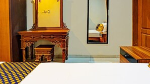 Un dormitorio con un aparador de madera, un espejo y una cama con colcha a lunares azules y amarillos.