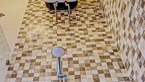 Un baño con piso de baldosas a cuadros y ducha con cabezal de mano.