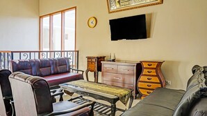 Una sala de estar con un sofá, una mesa, un televisor y un reloj en la pared.