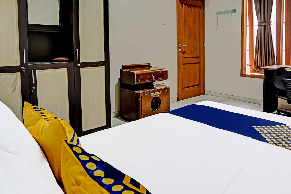 Une chambre d’hôtel avec un lit, un bureau, une armoire et une fenêtre avec des rideaux.