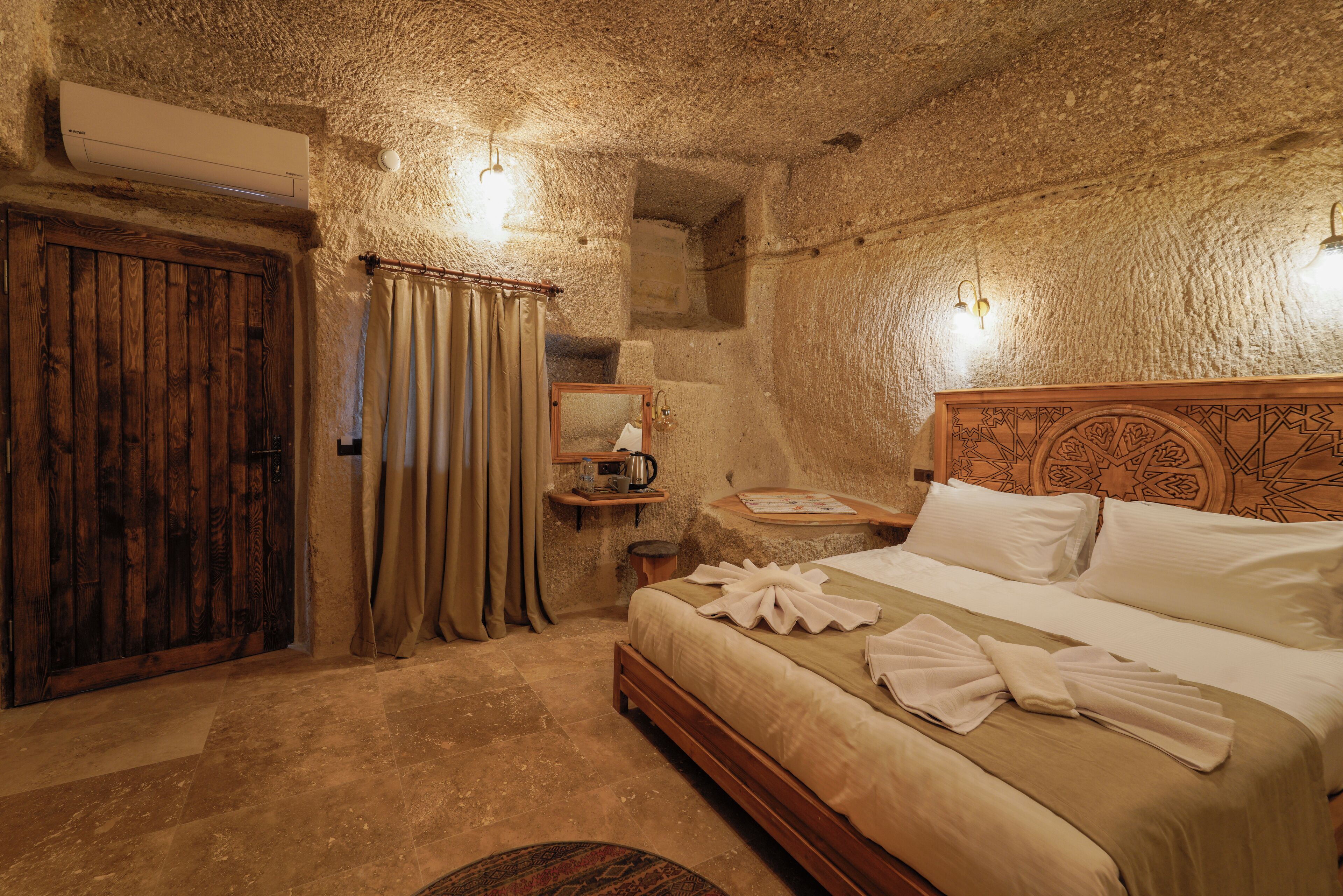 A rustic room with a stone wall, wooden bed, and a wooden door.