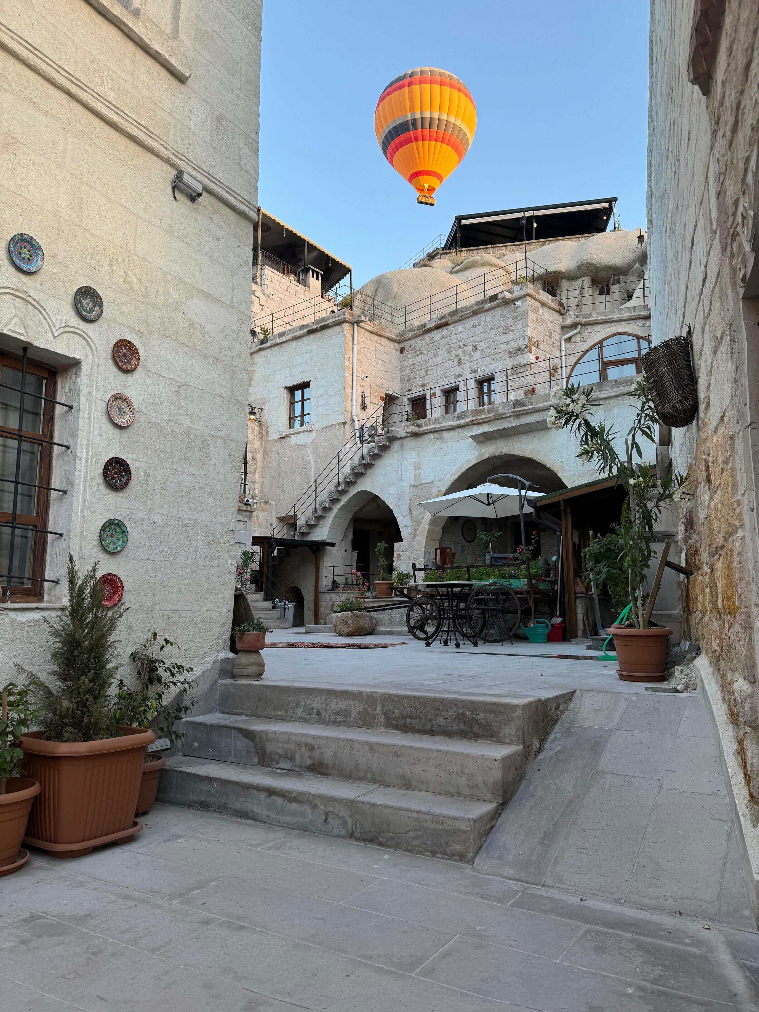 A courtyard with a hot air balloon, potted plants, and a staircase leading to an upper level.