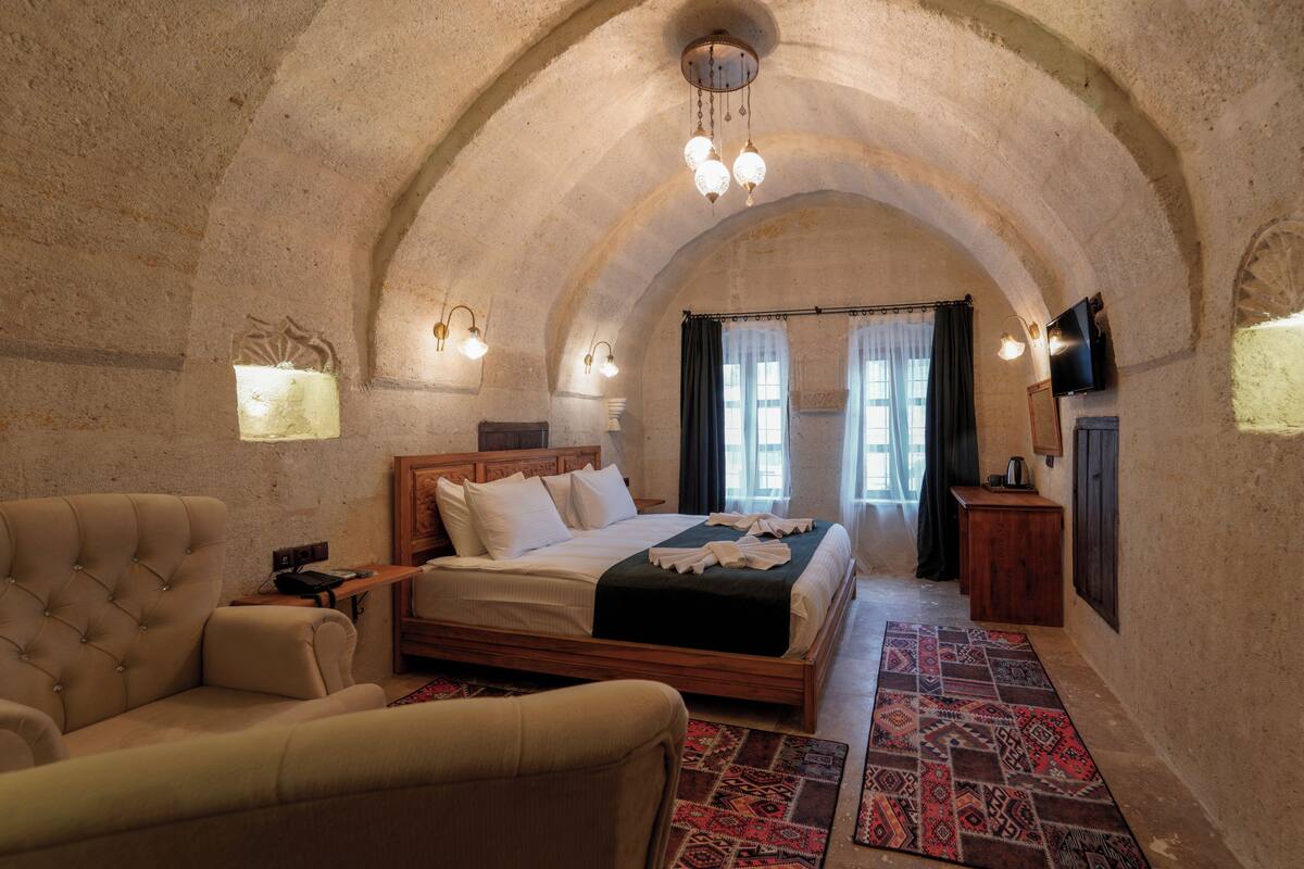 A bedroom with a large bed, a sofa, a TV, and a wooden cabinet.